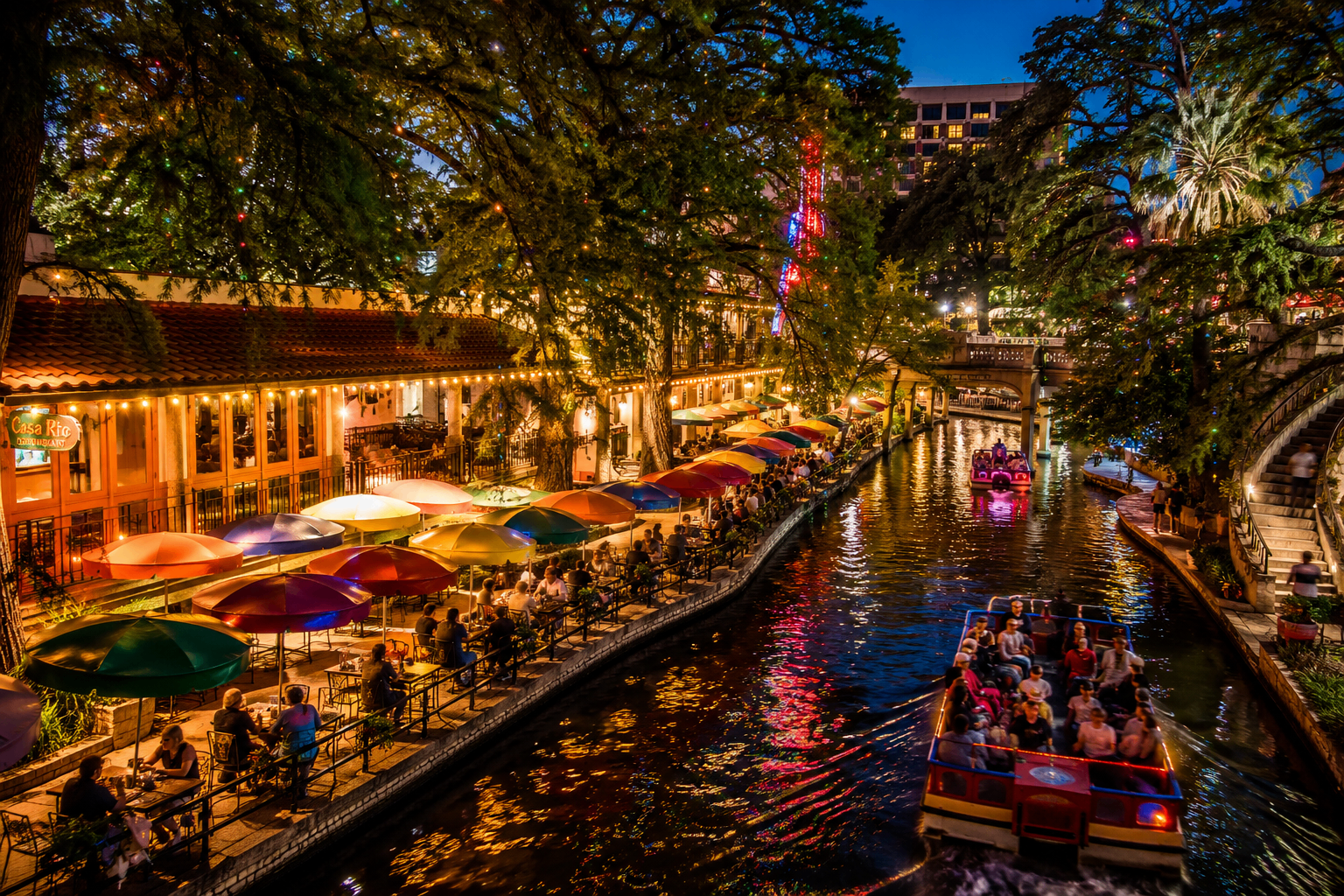 San Antonio Riverwalk at night with colorful umbrellas and boat tours